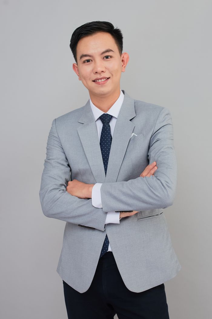 Smiling businessman in grey suit, arms crossed, professional look.